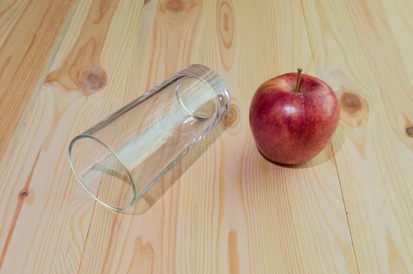 Domates ve elma ile ahşap bir arka plan üzerinde bir bardak suyu için boş cam