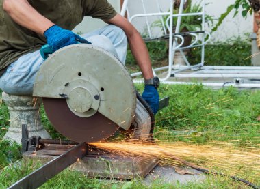 Tamirci metali parçalara ayırıyor. Salıncakları tamir etmek için çelik kesici kullanıyor..