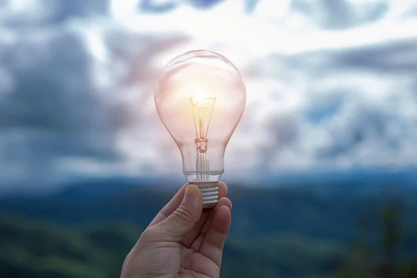 Doğaya karşı el ele tutuşan ampul, yenilenebilir enerji kaynakları için simgeler,