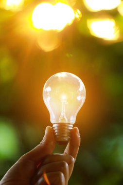 Doğaya karşı el ele tutuşan ampul, yenilenebilir enerji kaynakları için simgeler