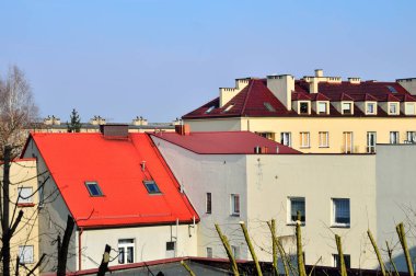 Mavi gökyüzü ve beyaz bulutlar güneşli bir günde renkli çatıların üzerinde.