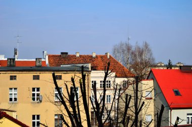 Mavi gökyüzü ve beyaz bulutlar güneşli bir günde renkli çatıların üzerinde.