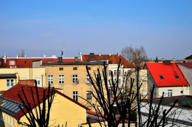 Mavi gökyüzü ve beyaz bulutlar güneşli bir günde renkli çatıların üzerinde.