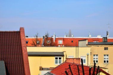 Mavi gökyüzü ve beyaz bulutlar güneşli bir günde renkli çatıların üzerinde.