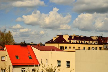 Mavi gökyüzü ve beyaz bulutlar güneşli bir günde renkli çatıların üzerinde.