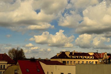 Mavi gökyüzü ve beyaz bulutlar güneşli bir günde renkli çatıların üzerinde.