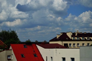 Mavi gökyüzü ve beyaz bulutlar güneşli bir günde renkli çatıların üzerinde.