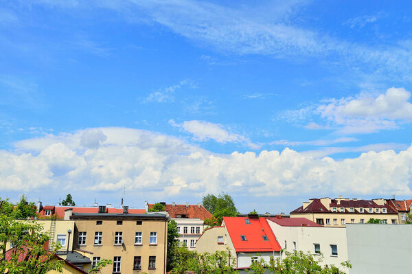Blue sky and white clouds over colorful roofs of houses on a sunny day.