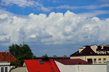 Mavi gökyüzü ve beyaz bulutlar güneşli bir günde renkli çatıların üzerinde.