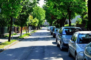 Yol ve park arabaları ağaçların altında, yukarıdaki parlak güneş.