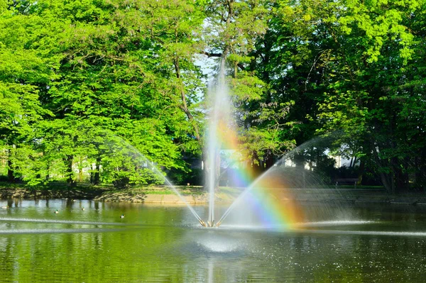 Fontána Tekoucí Vodu Přes Jezero Pozadí Zelených Stromů — Stock fotografie