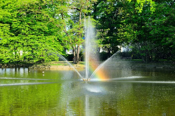 Fontána Tekoucí Vodu Přes Jezero Pozadí Zelených Stromů — Stock fotografie