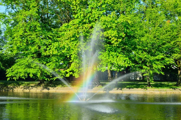 Fontána Tekoucí Vodu Přes Jezero Pozadí Zelených Stromů — Stock fotografie