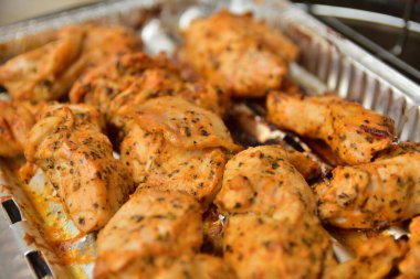 Izgara tepsisinde ekmek kırıntılarıyla kaplanmış tavuk parçaları..