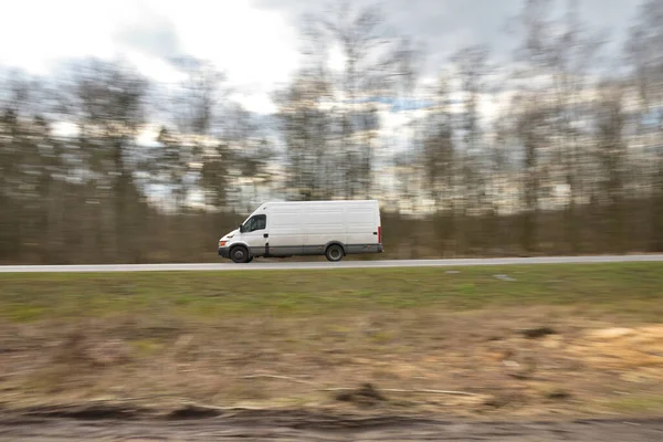 The sharp silhouette of the car in motion against the background of a blurred forest. Panoraming.