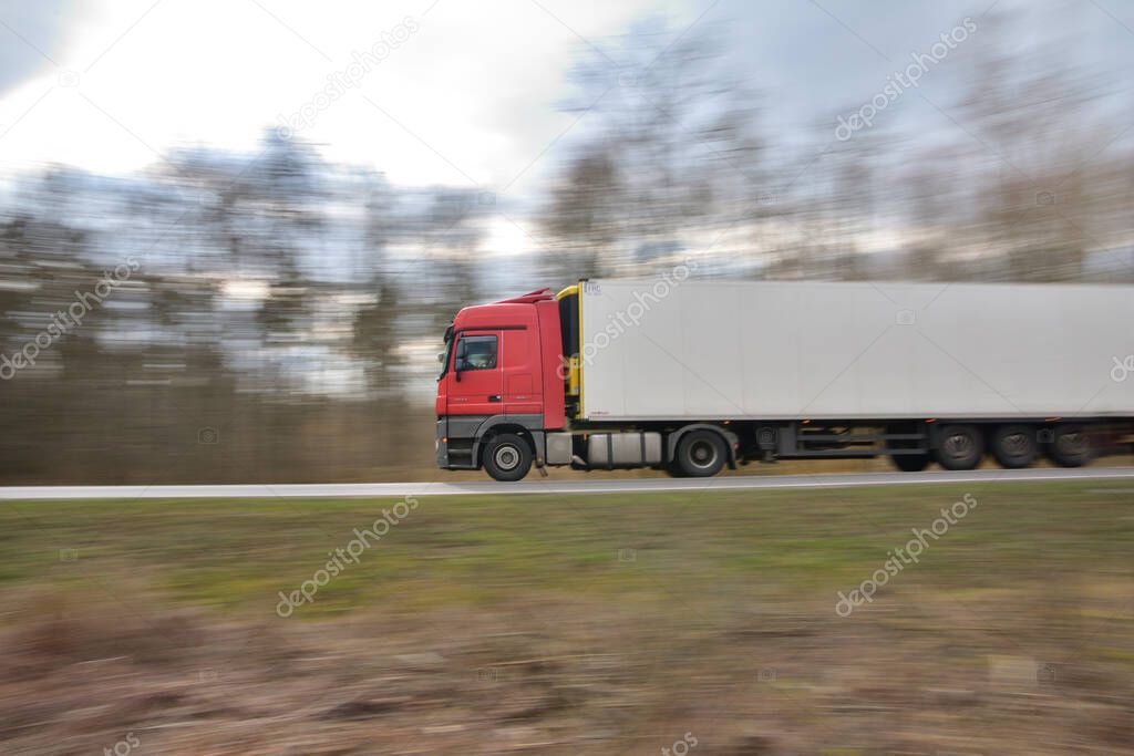 The sharp silhouette of the car in motion against the background of a blurred forest. Panoraming.