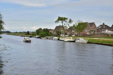 Hollanda 'daki evlerin yakınındaki kıyıya demirlemiş tekneler. Bahar.