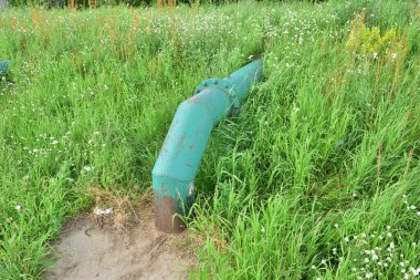 Yamaçtaki çimlerden çıkan bir boru. Yaz.