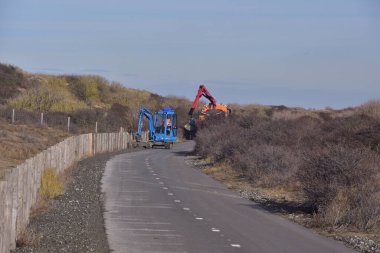 Hasarlı yol yüzeyini tamir ederken ağır yol makinesi. Güneşte.