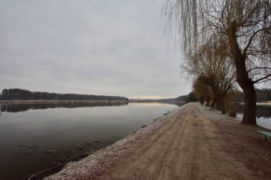 Geçit, soğuk bir sonbahar sabahında kasvetli bir sabahta göletin kıyısını nehirden ayırır. Soğuk.