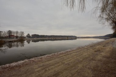 Geçit, soğuk bir sonbahar sabahında kasvetli bir sabahta göletin kıyısını nehirden ayırır. Soğuk.