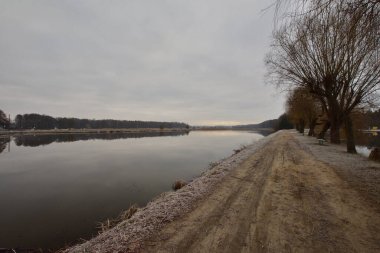 Geçit, soğuk bir sonbahar sabahında kasvetli bir sabahta göletin kıyısını nehirden ayırır. Soğuk.