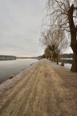 Geçit, soğuk bir sonbahar sabahında kasvetli bir sabahta göletin kıyısını nehirden ayırır. Soğuk.