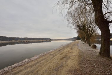 Geçit, soğuk bir sonbahar sabahında kasvetli bir sabahta göletin kıyısını nehirden ayırır. Soğuk.