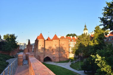 Varşova Eski Kasabası 'ndaki Barbican Kulesi doğmakta olan güneşin ışığında. Yaz.