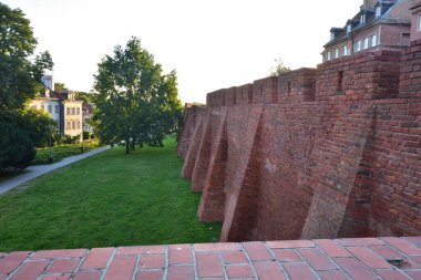 Güneş doğarken Varşova 'nın Eski Kasabası' ndaki Barbican 'ın tarihi savunma duvarları. Yaz.