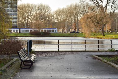 Kasvetli bir sonbahar sabahında, bir apartmanın yanındaki su kenarındaki boş bank..
