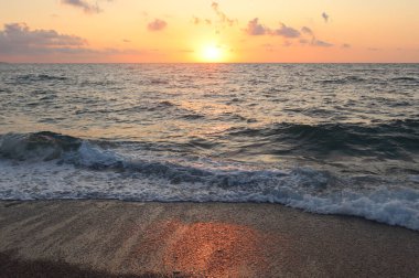 Deniz kıyısında resim gibi gün batımı. Güneş ıslak kuma yansıyor..