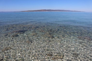 Hırvat sahilinde bir sahil. Açık gök mavisi suyun içinden ufuk çizgisinde Brach adasını görebilirsin.