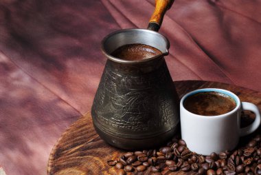 Cezve 'de kahve ve kırmızı arka planda beyaz bardak.