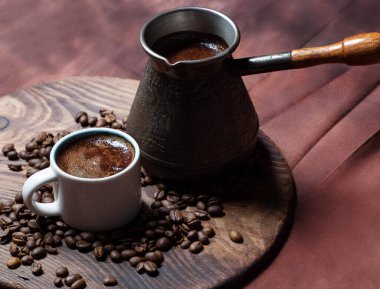 Cezve 'de kahve ve kırmızı arka planda beyaz bardak.