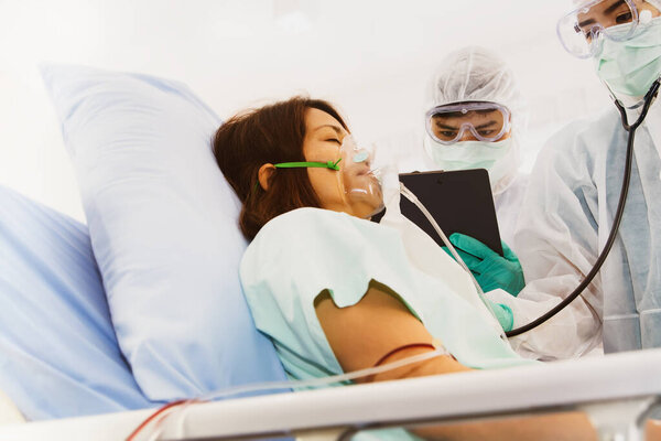Asian female patient with coronavirus infection Covid-19 lay in bed, the patient is treated and carefully cared for by the team of doctors in the hospital.