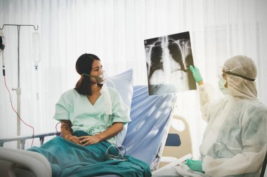 Grip salgını üniforması giyen kadın doktor kadın hastaların akciğerlerinde anormallikler görmesi için röntgen filmi taşıyor. Hastanedeki karantina odasındayken çekilmiş bir fotoğrafı.