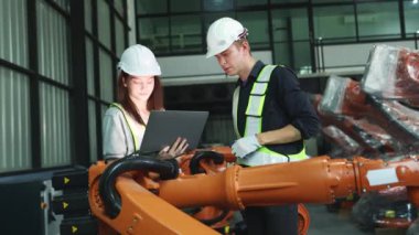 Erkek ve kadın elektrikçi robot mühendisi, depo modern iş sektörü 4.0 'da dizüstü bilgisayar elektronik otomasyon sistemi kurulumu ile yeni kaynak robotu test etme sürecini denetliyor.