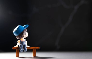 Çizgi film boyutunda bir adam masada oturuyor ve sırtına bakıyor.