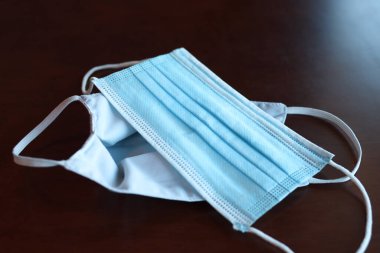 Tahta masadaki koruyucu maske ağzı ve burnu örtmek için General 3 katmanlı maske. (Solunum enfeksiyonlarını önleme kavramı) Kulaklıklı cerrahi maske. COVID 19