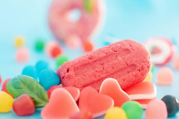 A pink doughnut and an ice cream with fruits and candy in a blue background