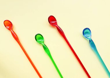 Sarı kağıt arka planda renkli plastik kaşıklar 