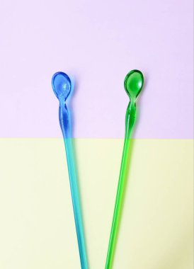 Sarı kağıtta mavi ve yeşil plastik kaşıklar 