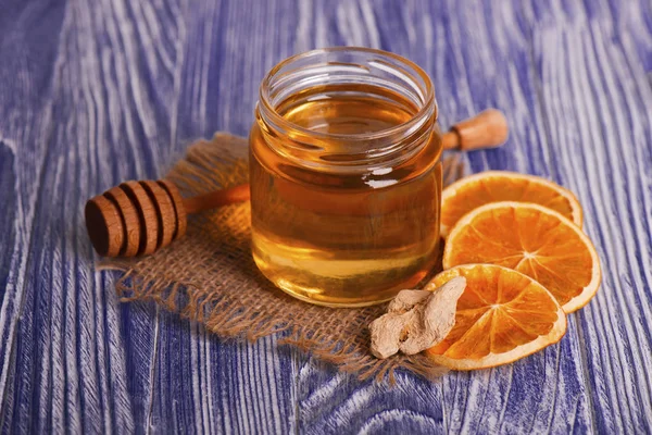 Honey in glass jar, ginger and dry slices of orange on vintage wooden background. Aromatic spices. — Stock Photo, Image