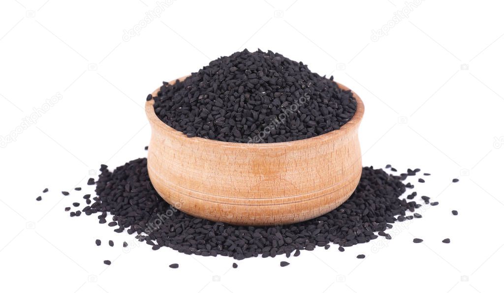 Black cumin seeds in wooden bowl, isolated on white background. Nigella sativa.