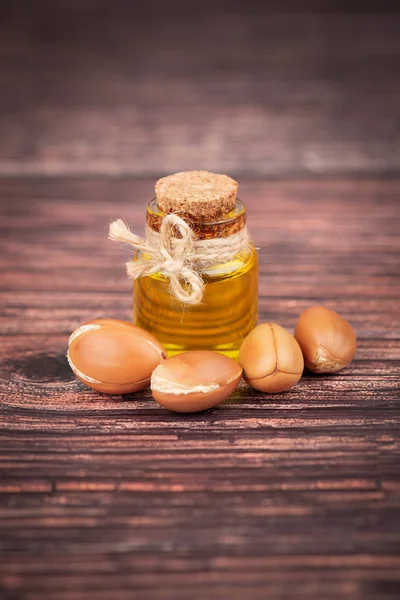 Argan yağı, ahşap arka plan üzerine. Kozmetik ve güzellik ürünleri için Argan fıstığı ve tohumu. Fas doğal argan meyve.