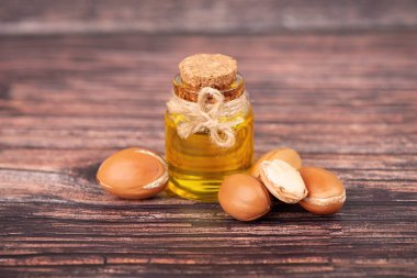 Argan yağı, ahşap arka plan üzerine. Kozmetik ve güzellik ürünleri için Argan fıstığı ve tohumu. Fas doğal argan meyve.