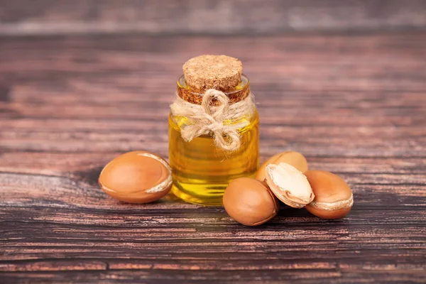 Óleo de Argan, sobre fundo de madeira. Nozes e sementes de Argan, para produtos cosméticos e de beleza. Fruta de argan natural de Marrocos . — Fotografia de Stock