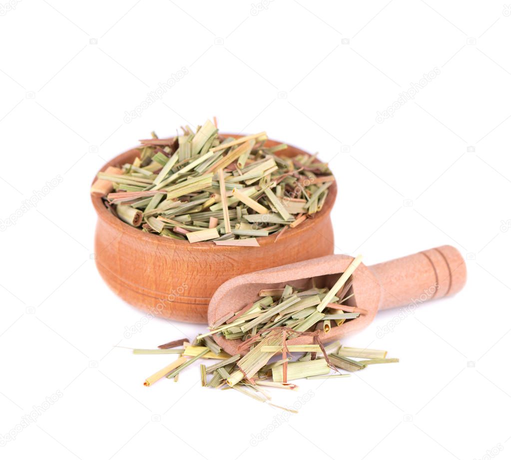 Lemongrass in a wooden bowl and spoon, isolated on a white background. Dry sprigs of natural lemongrass.