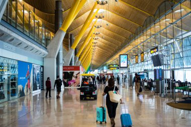 Madrid havaalanında çantalı bir kadın uçmak için yürüyor.